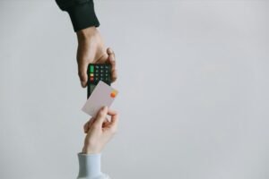 A person holds a credit card in one hand and a remote control in the other, suggesting a shopping or entertainment context.